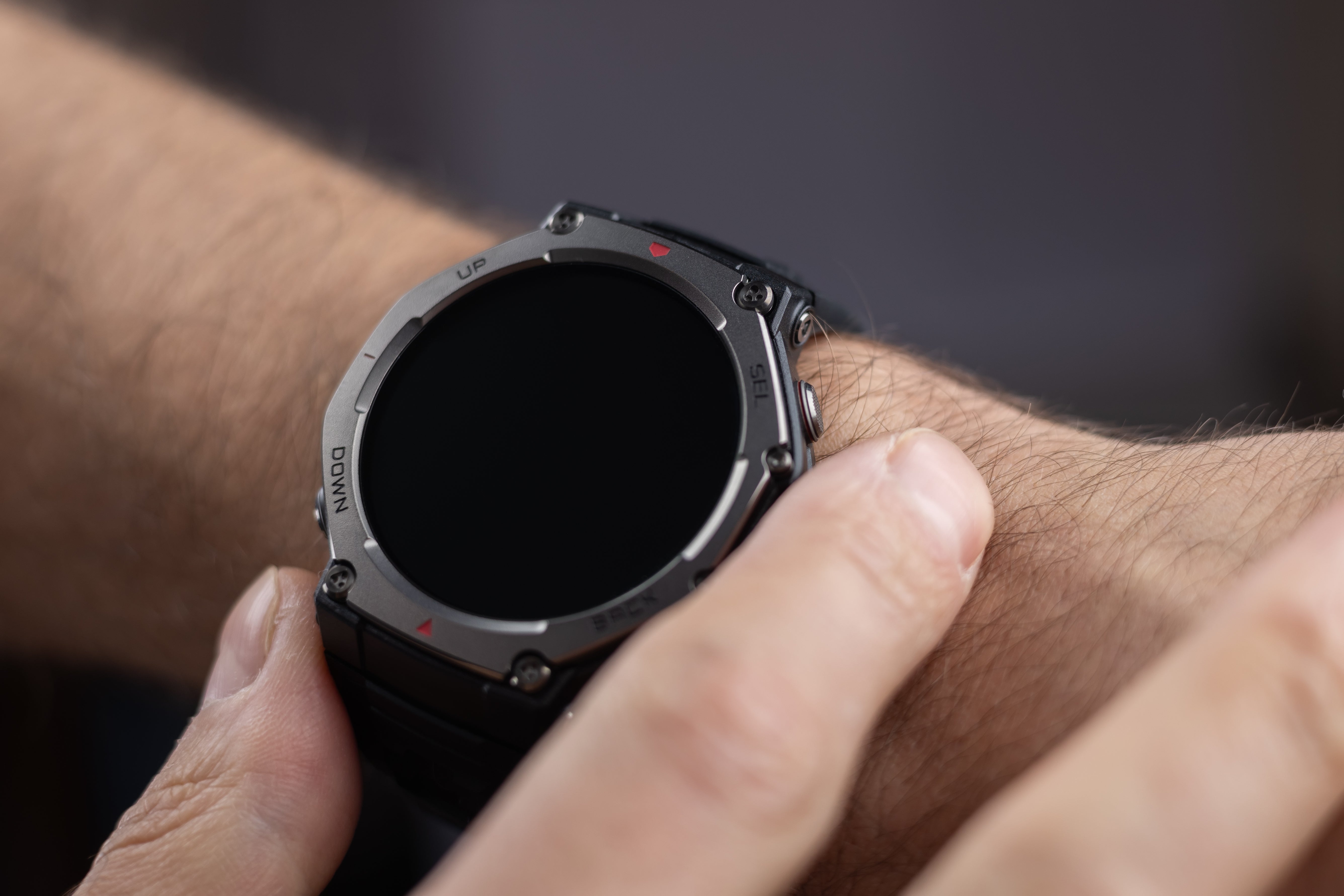 Homme qui porte à son poignet une montre connectée design noire et gris foncé.